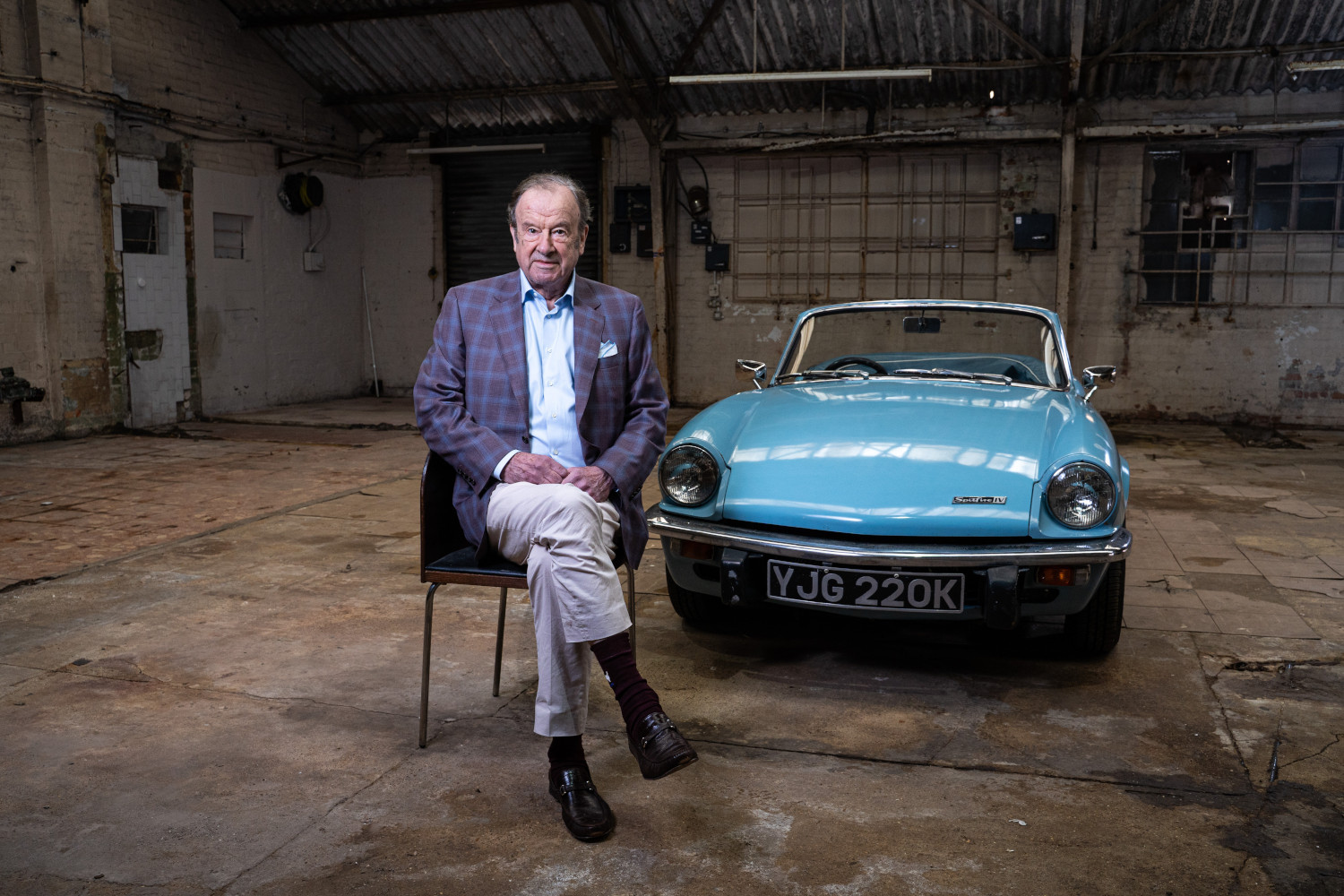 John Mills in front of a classic car