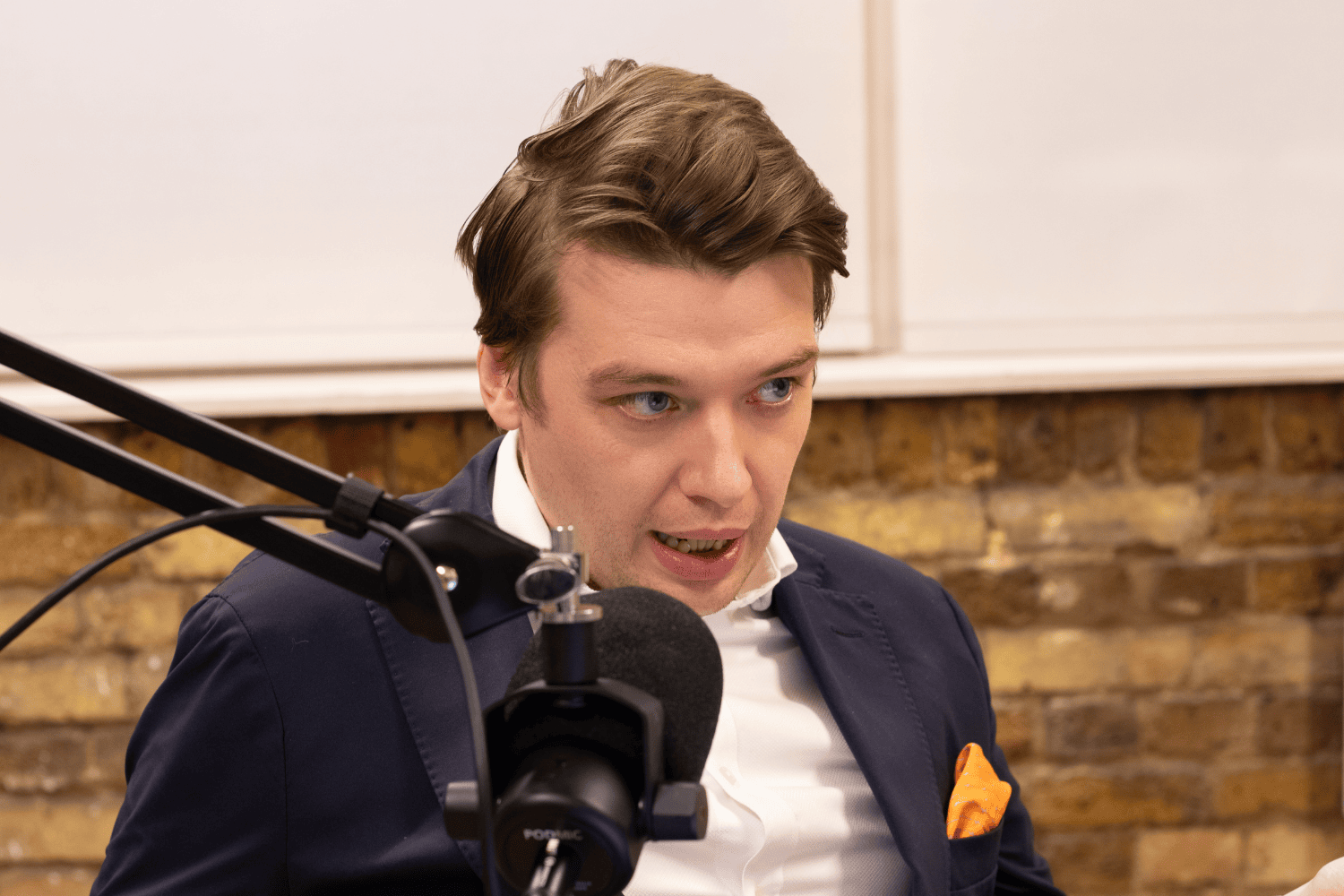 A podcast host speaking into a microphone during a recording session at the Profile studio.